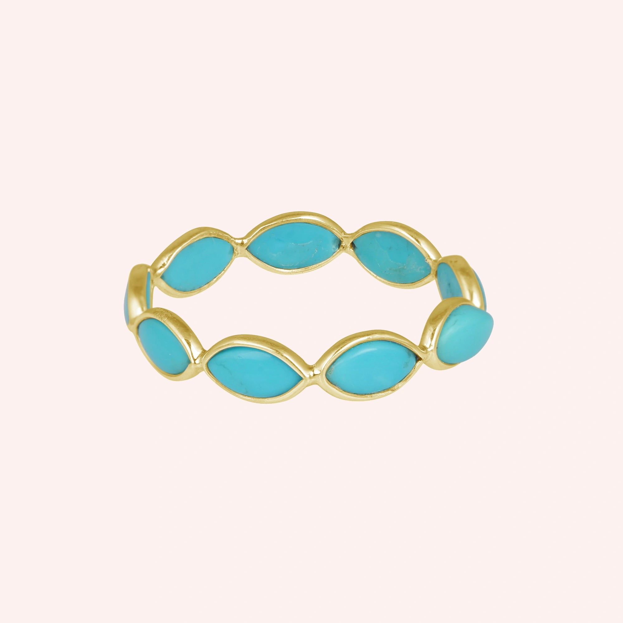 Gold plated silver eternity ring with marquise cut turquoise gemstones set straight on view against light pink background