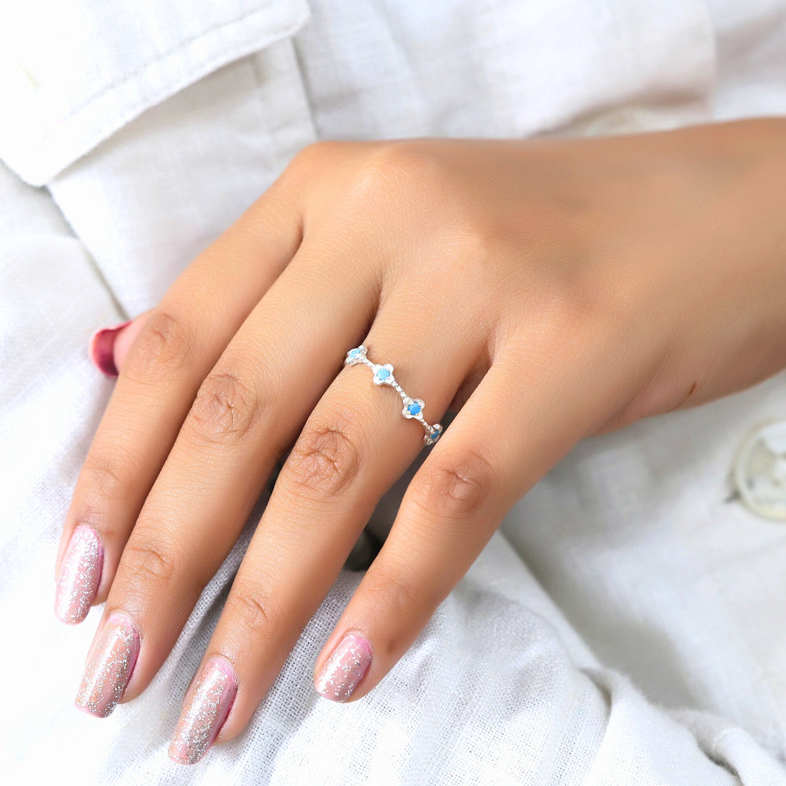 Sterling silver turquoise flower ring with blue turquoise stones on a wrinkled white velvet background viewed at an angle.