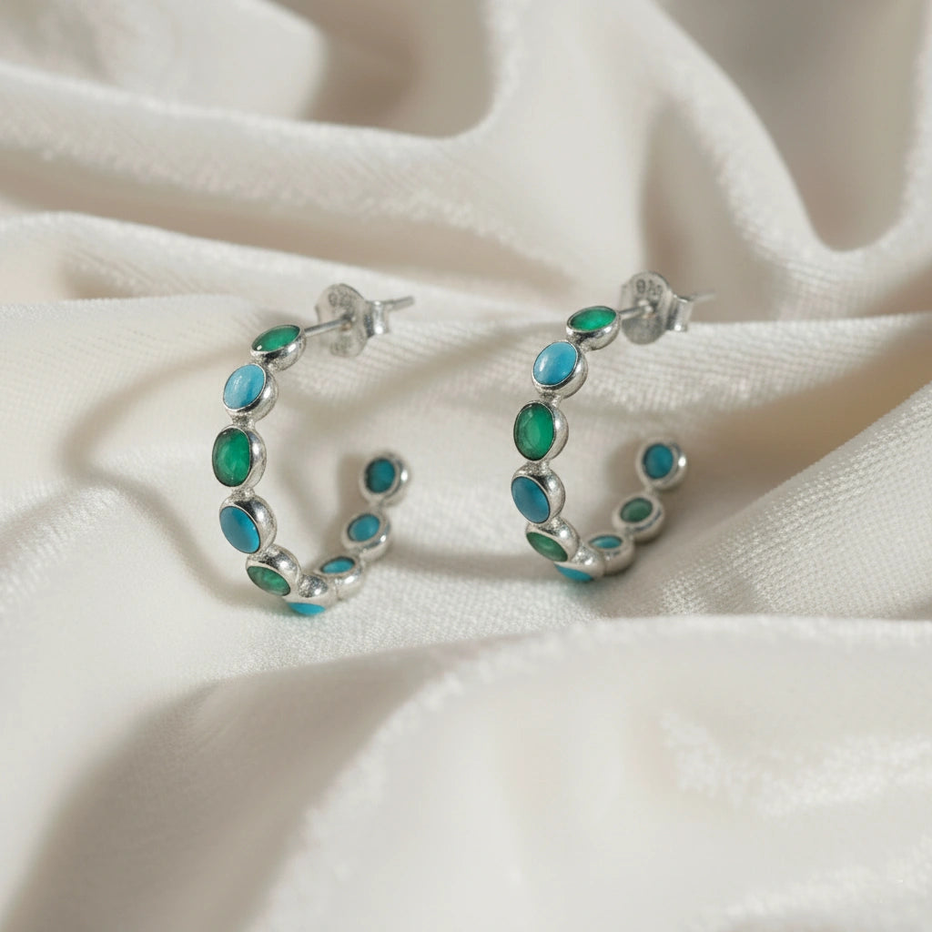 Sterling silver garnet bracelet with heart shaped red stones on a wrinkled white velvet angled view showing detail.