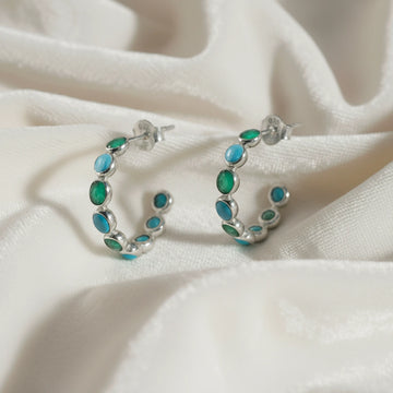 Sterling silver garnet bracelet with heart shaped red stones on a wrinkled white velvet angled view showing detail.