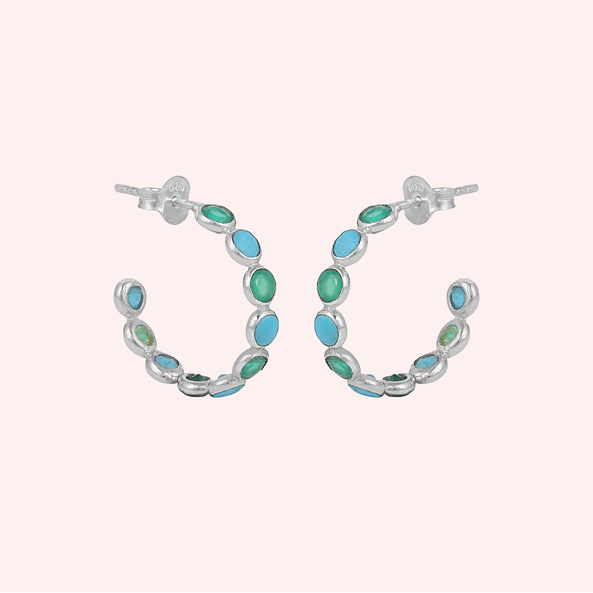 Sterling silver turquoise hoop earrings with green onyx stones a beautiful product focus on a pink background straight on view