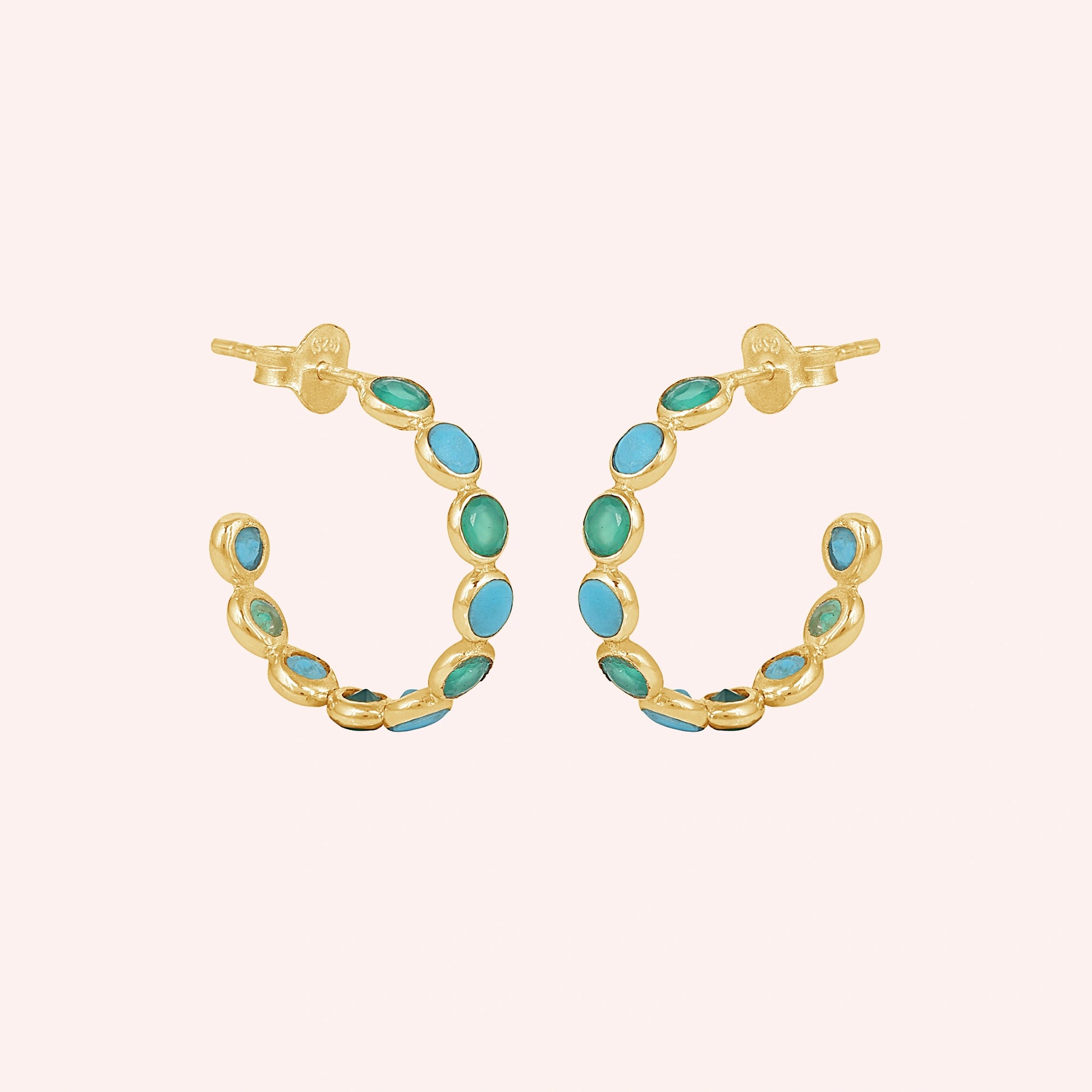 Gold vermeil onyx hoop earrings with turquoise stones a beautiful product on a light pink background straight on view.