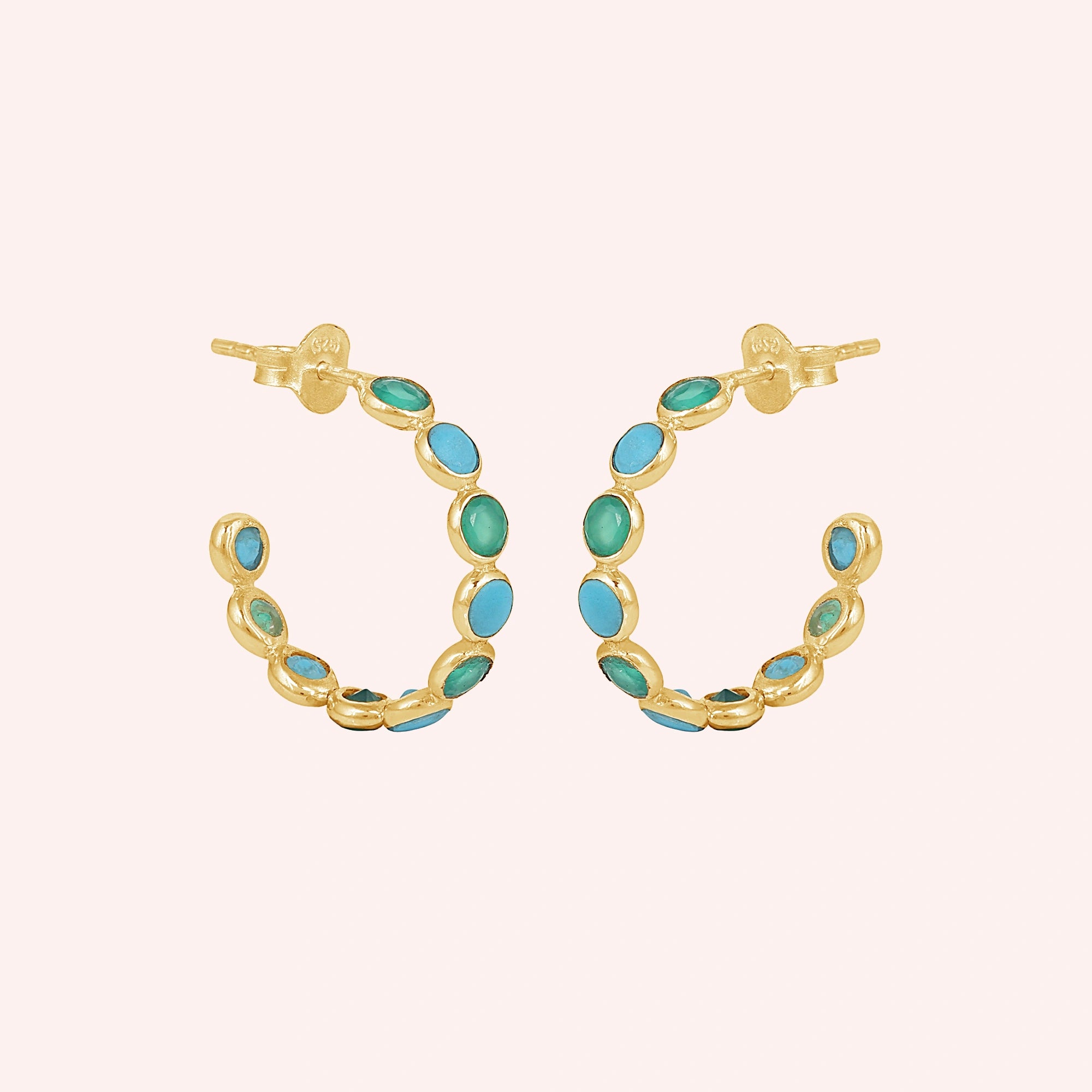 Gold vermeil onyx hoop earrings with turquoise stones a beautiful product on a light pink background straight on view.