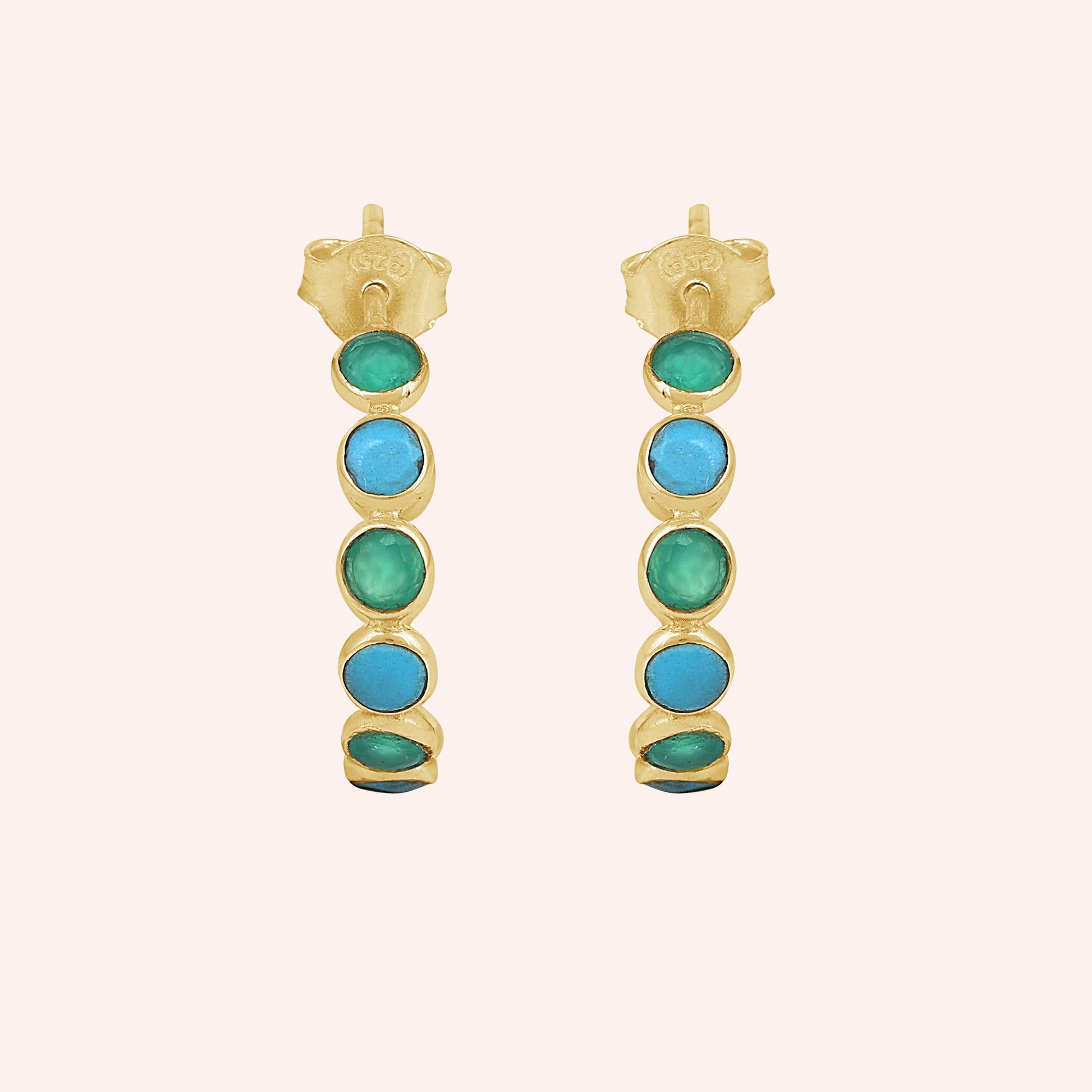 Gold vermeil turquoise hoop earrings with green onyx stones a beautiful product on a light pink background straight on view.