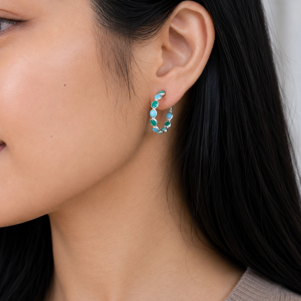 Side angle view of silver turquoise hoop earring with green stones worn on the ear