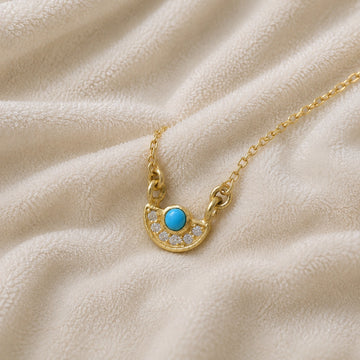 Turquoise_necklace_in_gold_plated_silver_with_turquoise_and_CZ_stones_at_slight_angle_view_on_soft_fabric_background