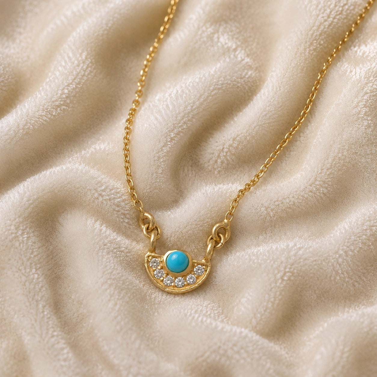 Turquoise_necklace_in_gold_plated_silver_with_turquoise_and_CZ_stones_at_front_angle_view_on_soft_fabric_background