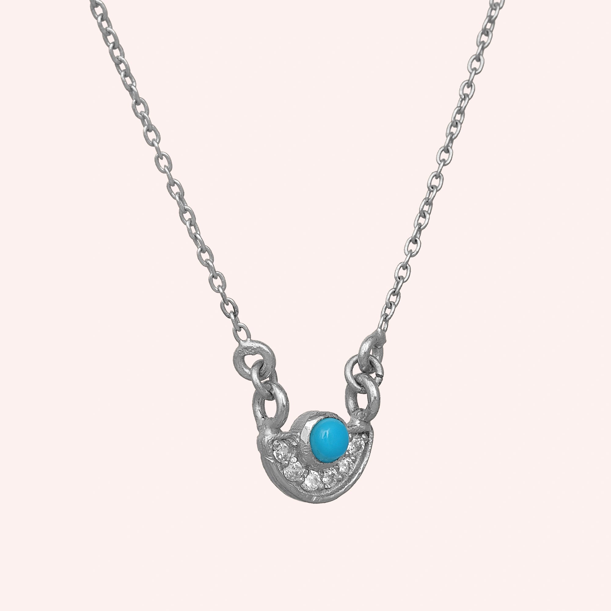 Turquoise_necklace_in_sterling_silver_with_turquoise_and_CZ_stones_at_slight_angle_view_on_solid_pink_background