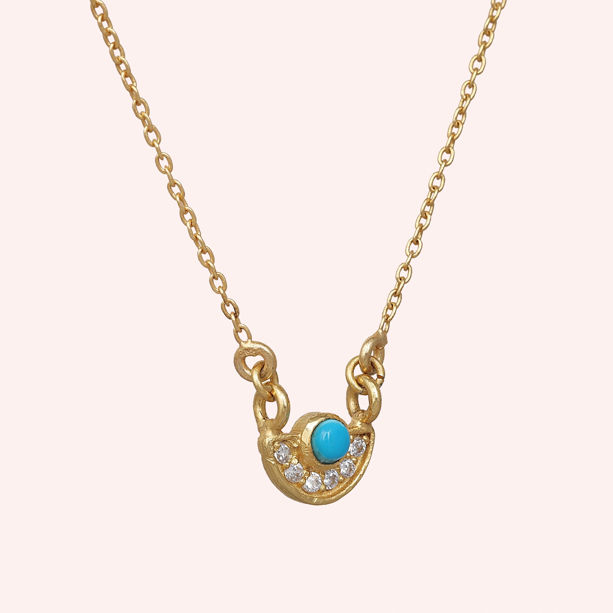 Turquoise_necklace_in_gold_plated_silver_with_turquoise_and_CZ_stones_at_slight_angle_view_on_solid_pink_background