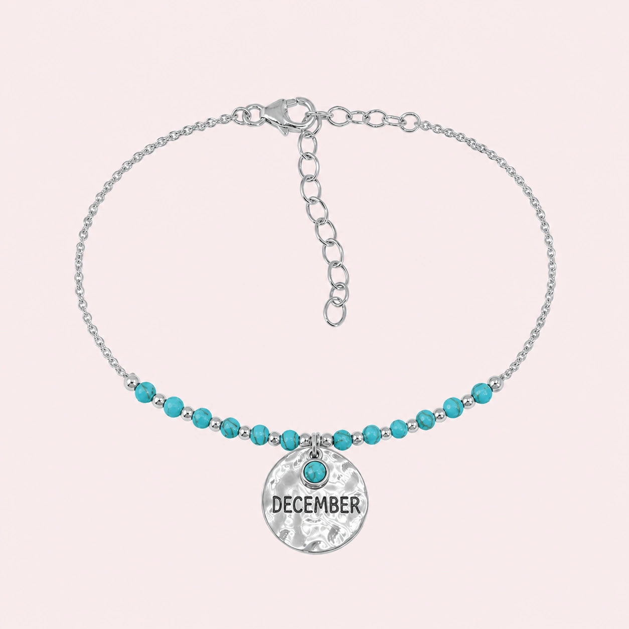 Birthstone_bracelet_in_sterling_silver_with_December_charm_and_turquoise_beads_on_fine_chain_on_solid_pink_background