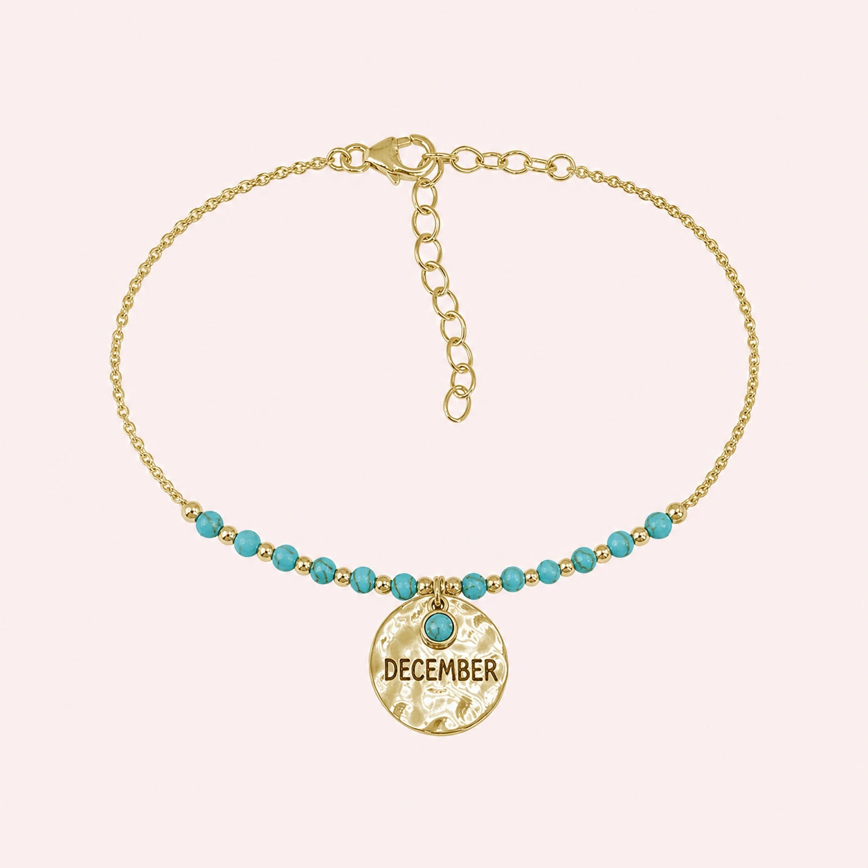 Birthstone_bracelet_in_gold_plated_silver_with_December_charm_and_turquoise_beads_on_fine_chain_on_solid_pink_background