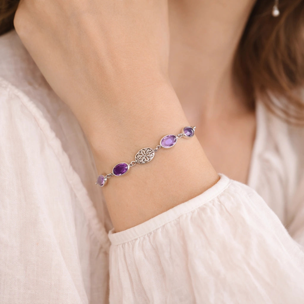 vintage_amethyst_bracelet_side_angle_worn_on_wrist_with_oval_purple_gemstones_amethyst_tennis_bracelet_soft_fabric_background