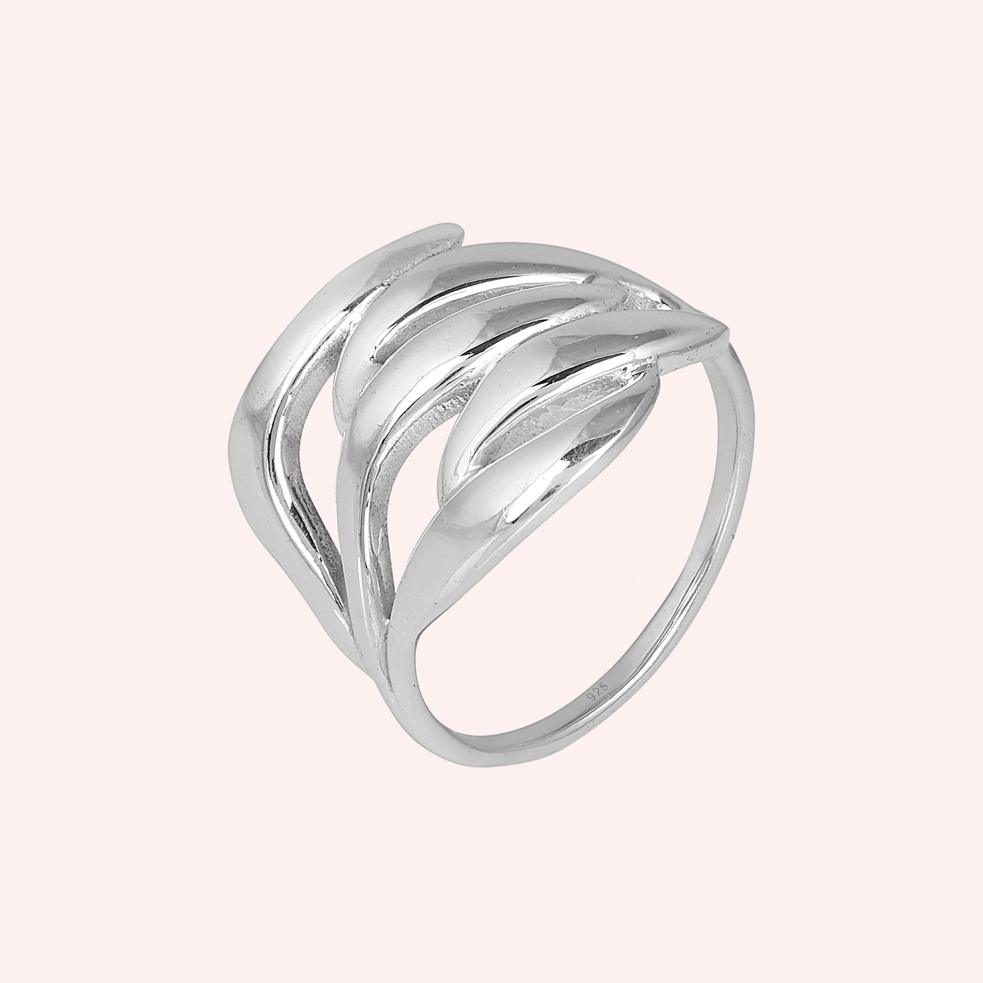 wave ring featuring a flowing silver design as a statement ring over a pale pink background from a side profile angle