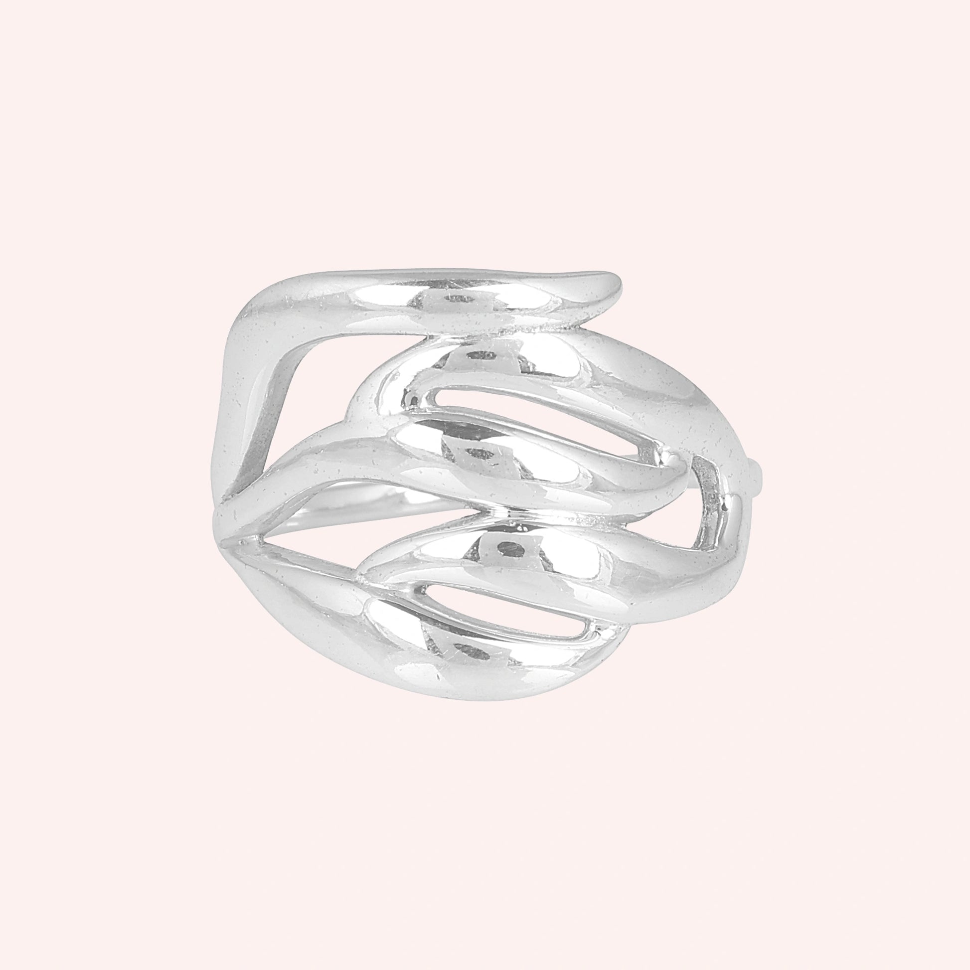 wave ring featuring a flowing silver design as a statement ring over a pale pink background from a front on angle