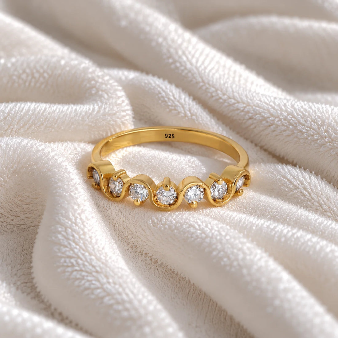 Wave_ring_in_gold_plated_silver_in_half_eternity_design_with_CZ_stones_at_front_angle_view_on_soft_fabric_background