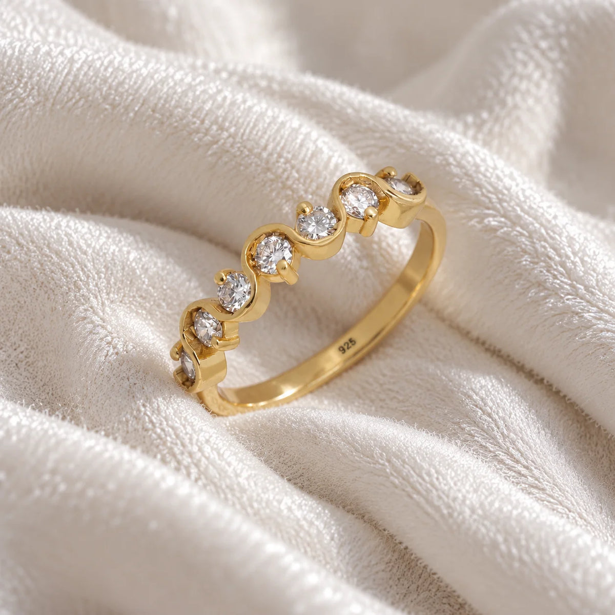 Wave_ring_in_gold_plated_silver_in_half_eternity_design_with_CZ_stones_at_side_view_on_soft_fabric_background