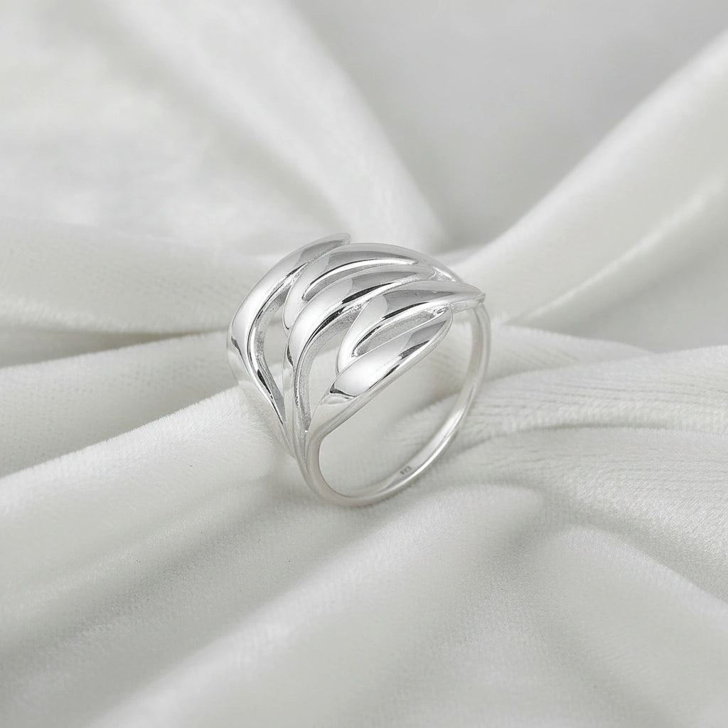 wave ring featuring a flowing silver design as a statement ring over white fabric from a side-top view angle