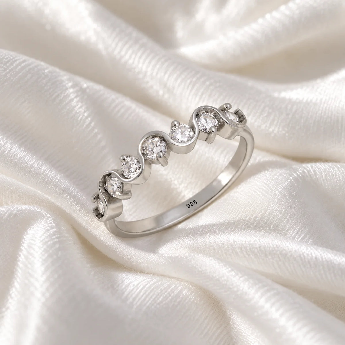 Wave_ring_in_sterling_silver_in_half_eternity_design_with_CZ_stones_at_side_view_on_soft_fabric_background