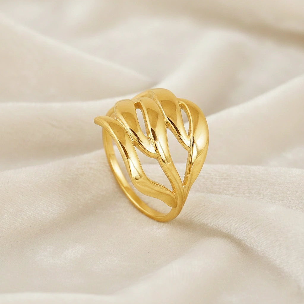 wave ring featuring a flowing gold-plated design as a statement ring over white fabric from a side-top view angle