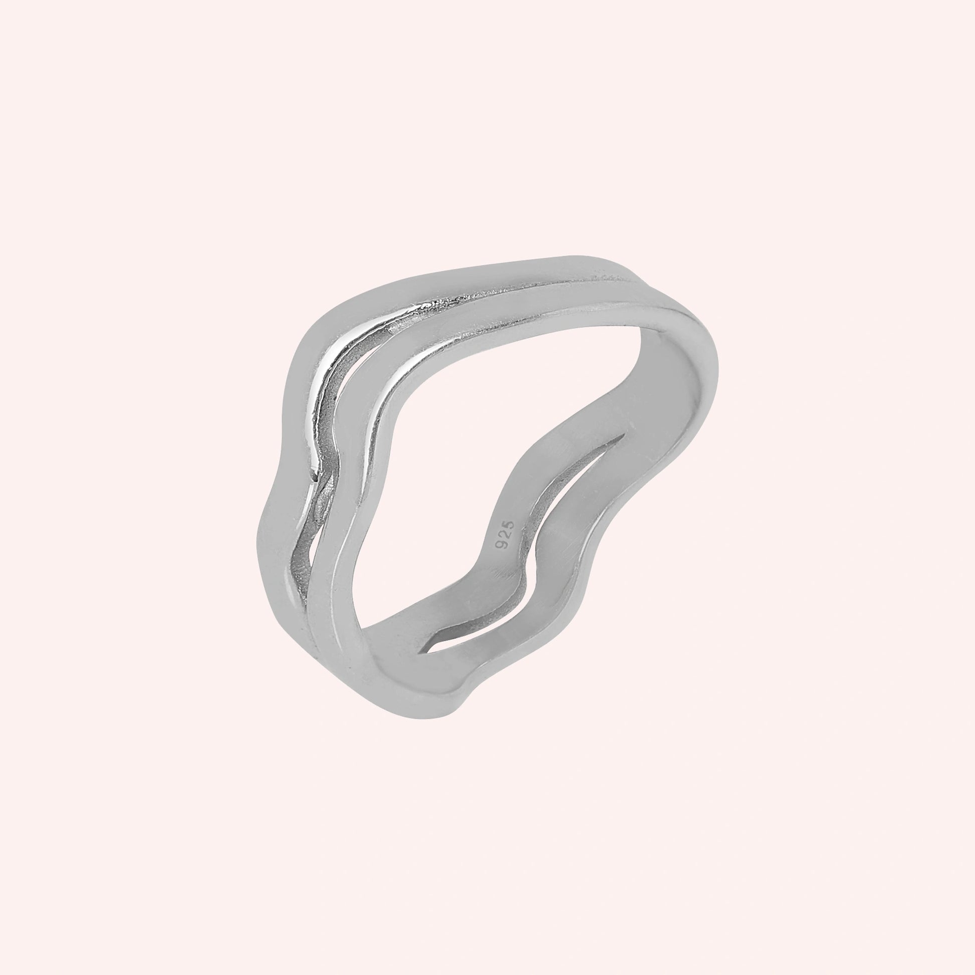 An angled view of a double layered wave ring silver band ring with 925 stamp with an organic shape on a light pink background