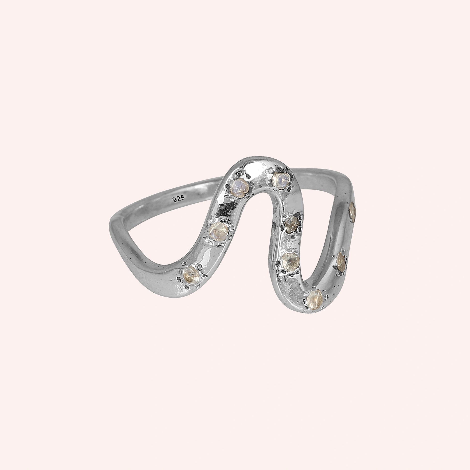 white topaz ring in sterling silver wave ring design shown at a front angled view with curved band on a pink background