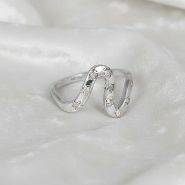 white topaz ring in sterling silver wave ring design shown at front angled view highlighting stones on white fabric background