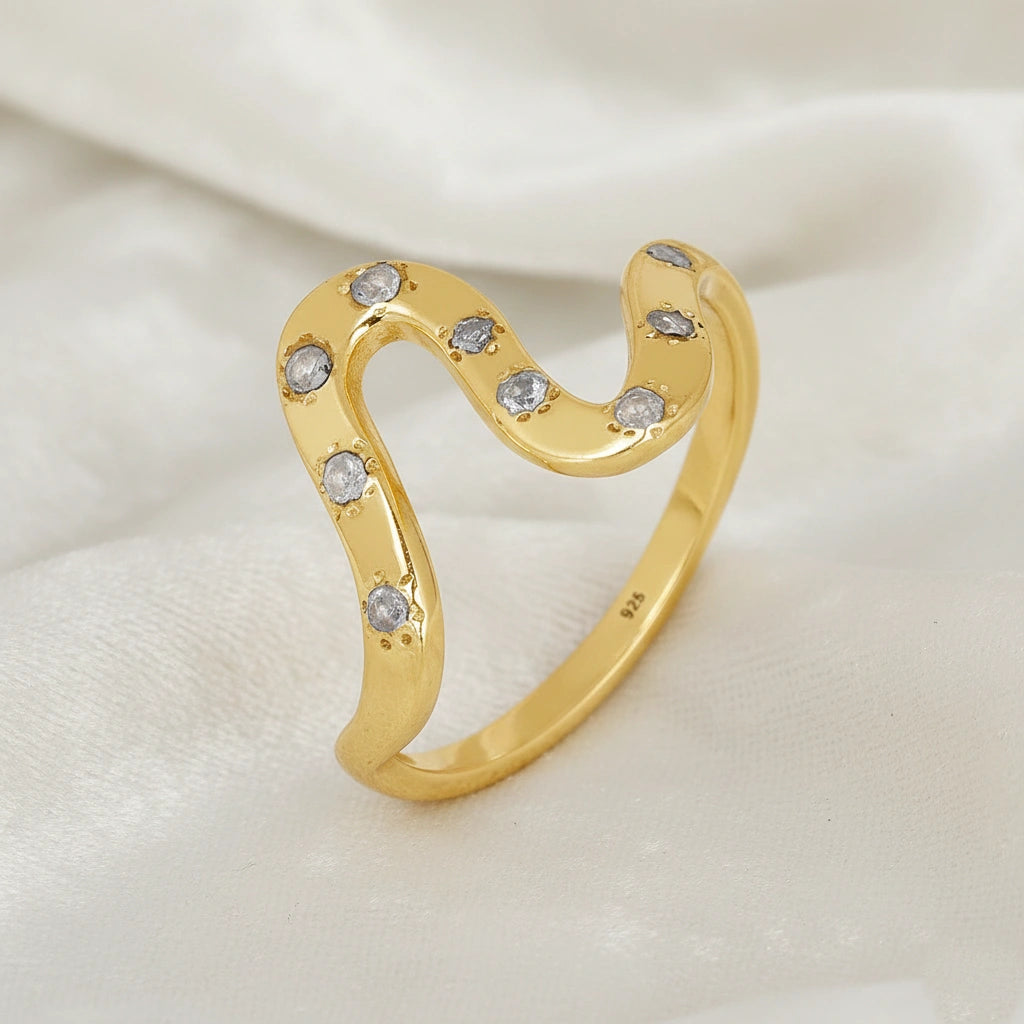 white topaz ring in gold plated sterling silver wave ring shown at side angled view showing stones on soft white fabric background