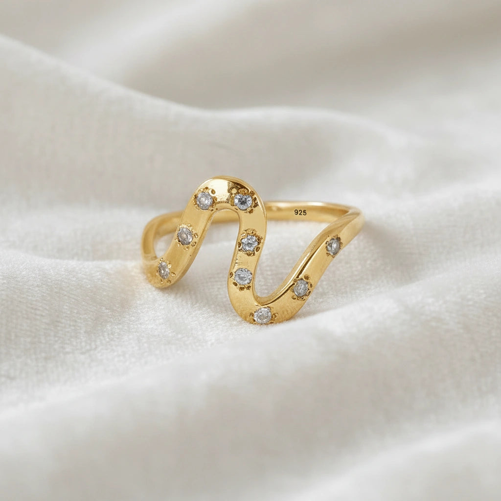white topaz ring in gold plated sterling silver wave ring shown at front angled view highlighting stones white fabric background