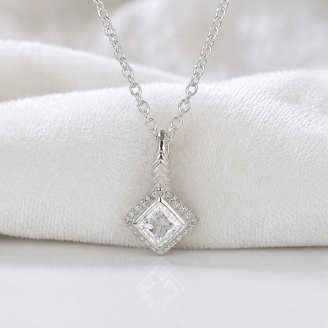 Birthstone_necklace_in_sterling_silver_with_square_cut_white_topaz_pendant_in_front_angle_view_on_soft_white_fabric_background