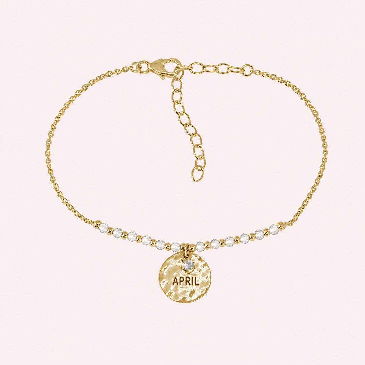 Birthstone_bracelet_in_gold_plated_silver_with_April_charm_and_white_topaz_beads_on_fine_chain_on_solid_pink_background