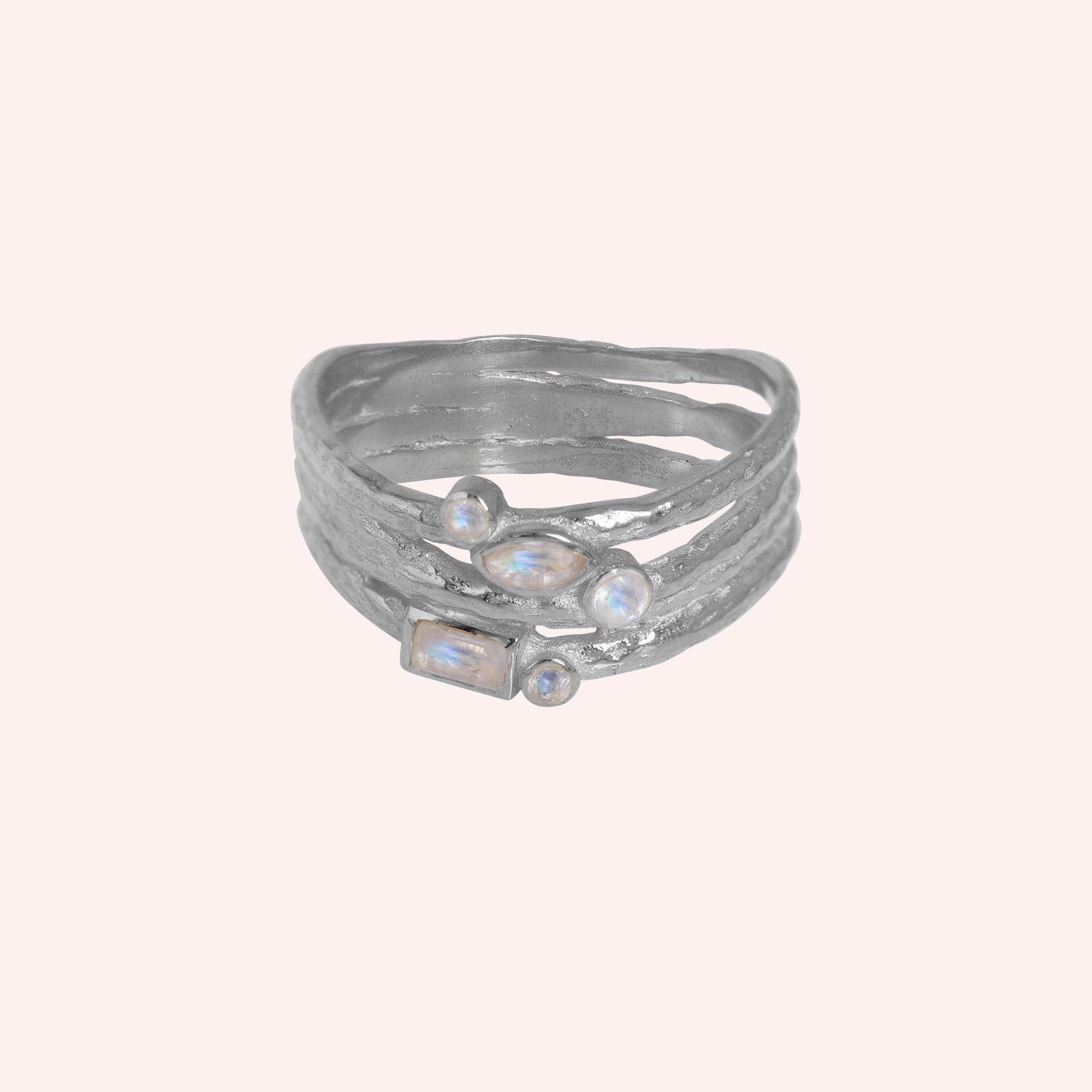 Wide_band_ring_in_sterling_silver_with_multiple_moonstones_shown_in_front_angle_view_on_solid_pink_background