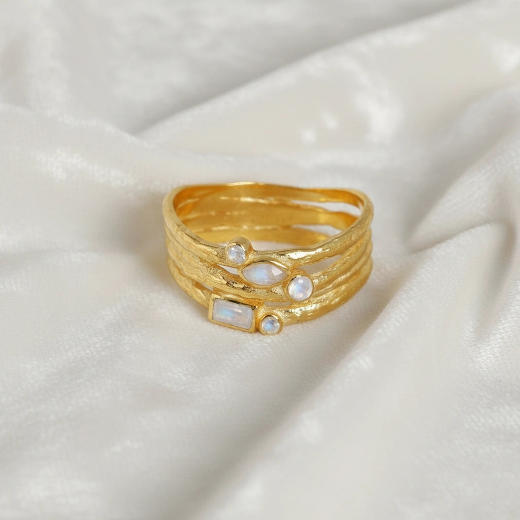 Wide_band_ring_in_gold_plated_silver_with_multiple_moonstones_shown_in_front_angle_view_on_soft_fabric_background