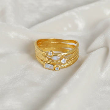Wide_band_ring_in_gold_plated_silver_with_multiple_moonstones_shown_in_front_angle_view_on_soft_fabric_background