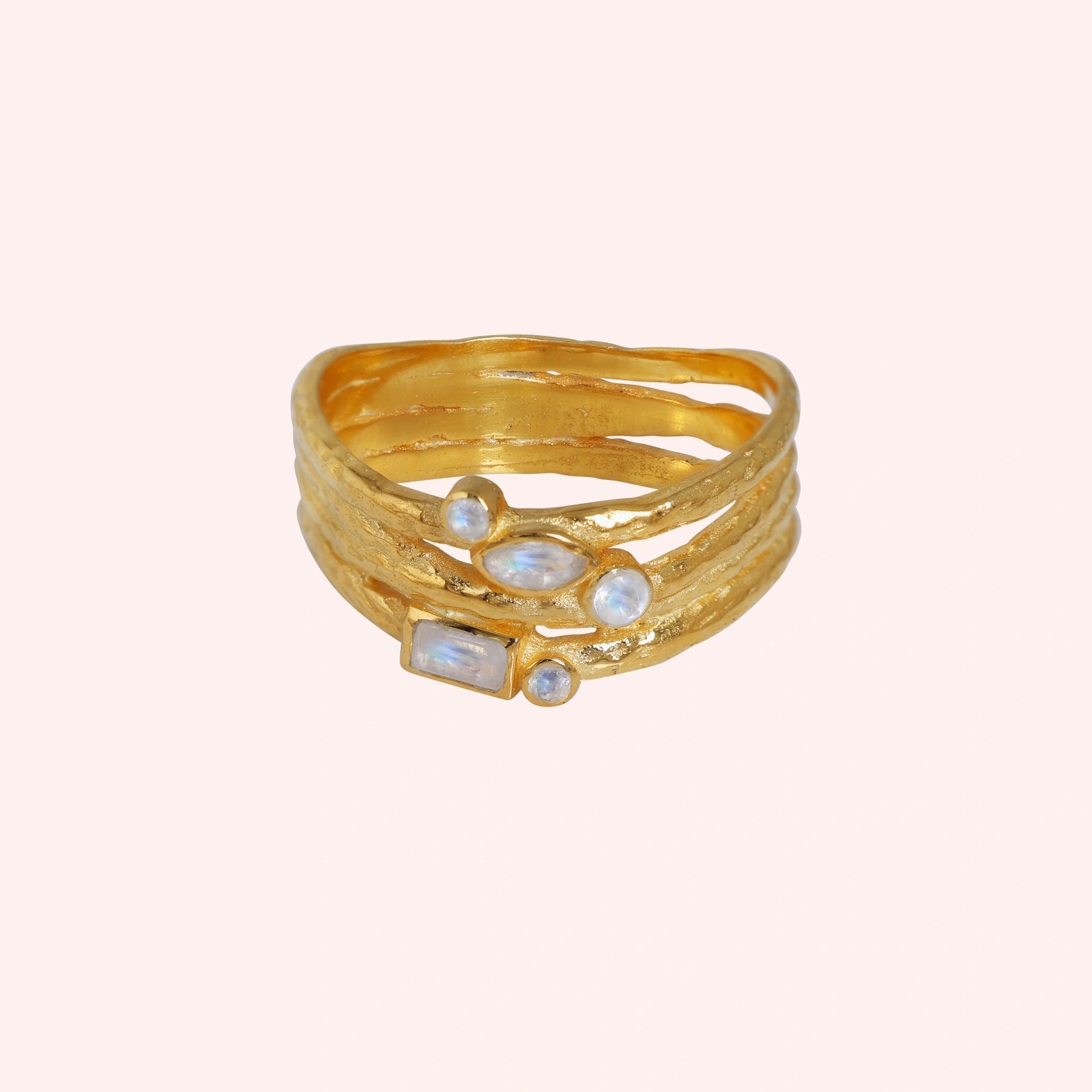 Wide_band_ring_in_gold_plated_silver_with_multiple_moonstones_shown_in_front_angle_view_on_solid_pink_background