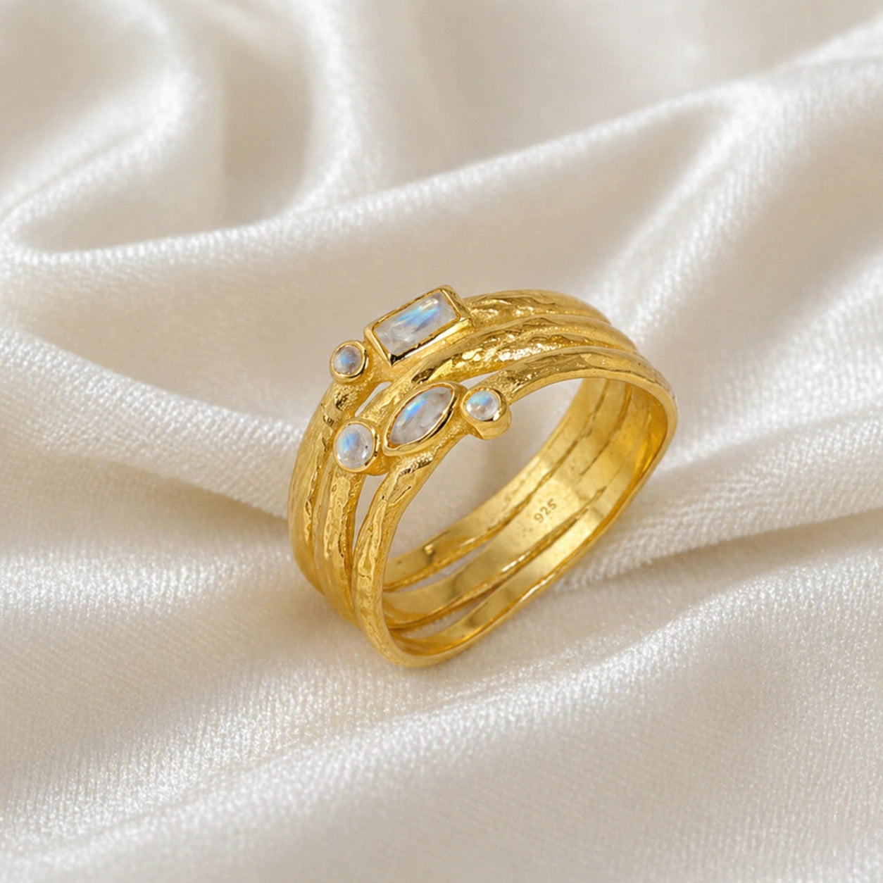 Wide_band_ring_in_gold_plated_silver_with_multiple_moonstones_shown_in_slightly_angled_view_on_soft_fabric_background