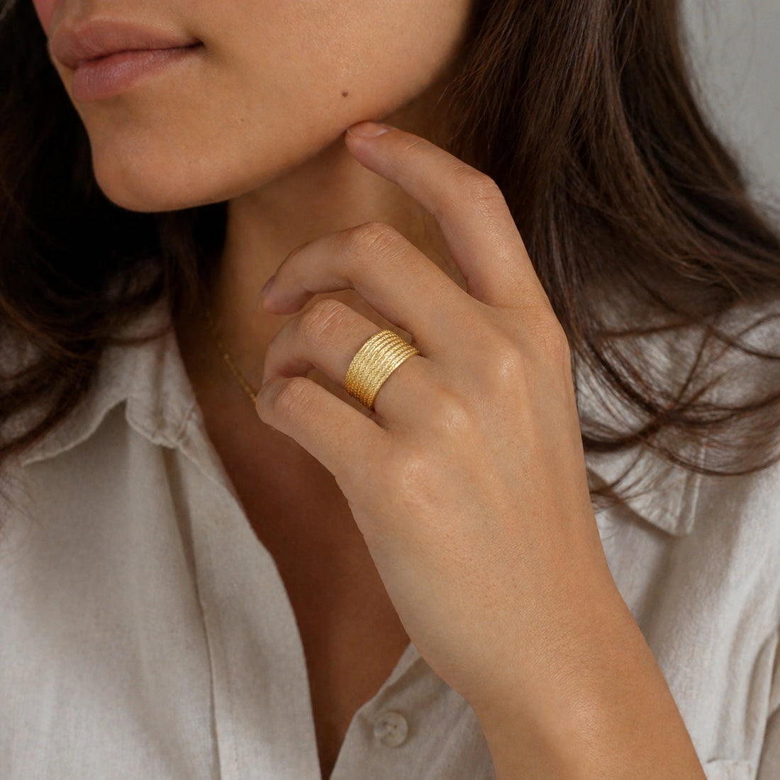 Wide_wedding_band_in_textured_gold_plated_silver_with_braided_pattern_in_slightly_angled_view_on_soft_fabric_background