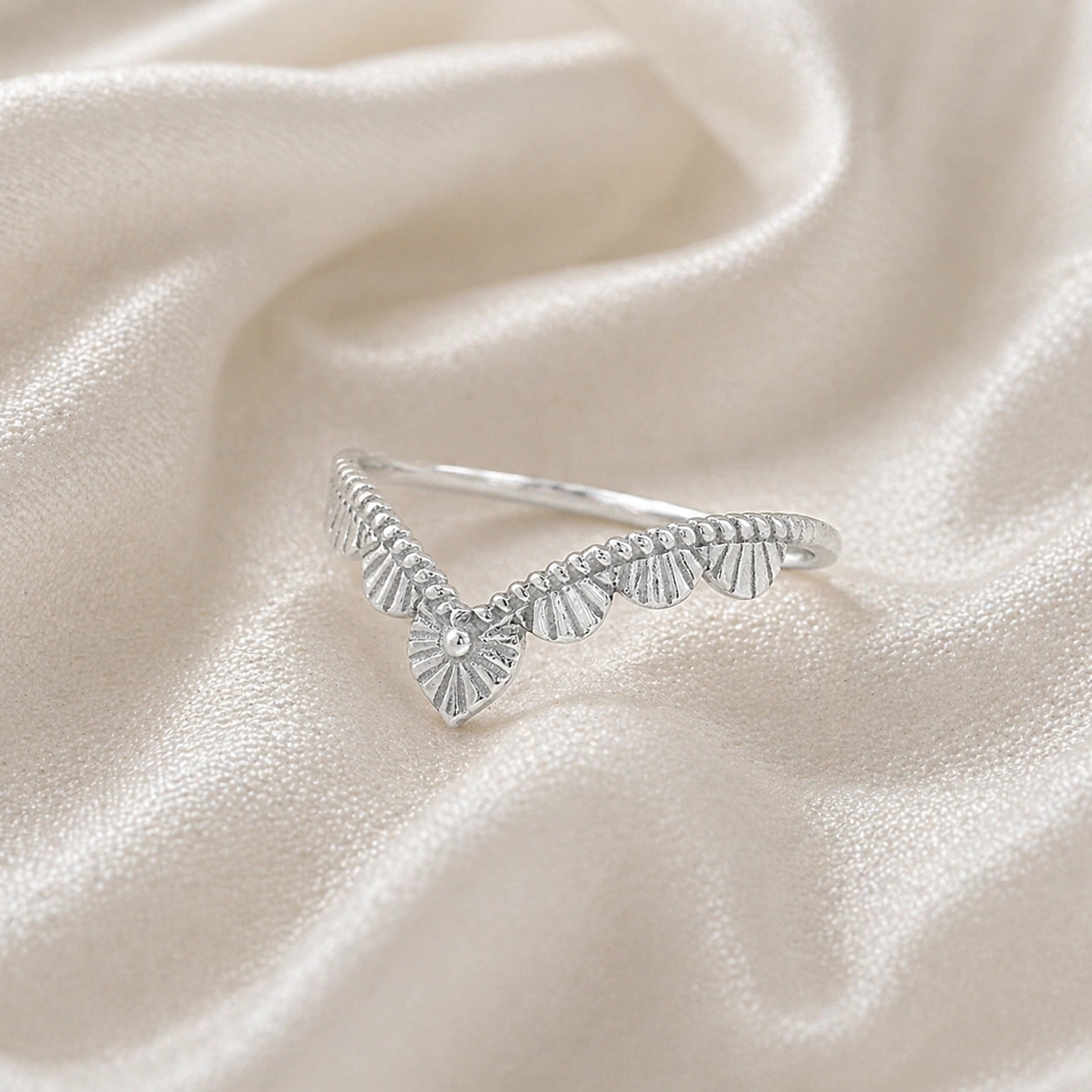 Wishbone_ring_in_sterling_silver_with_designed_v_shape_in_slightly_angled_view_on_soft_fabric_background