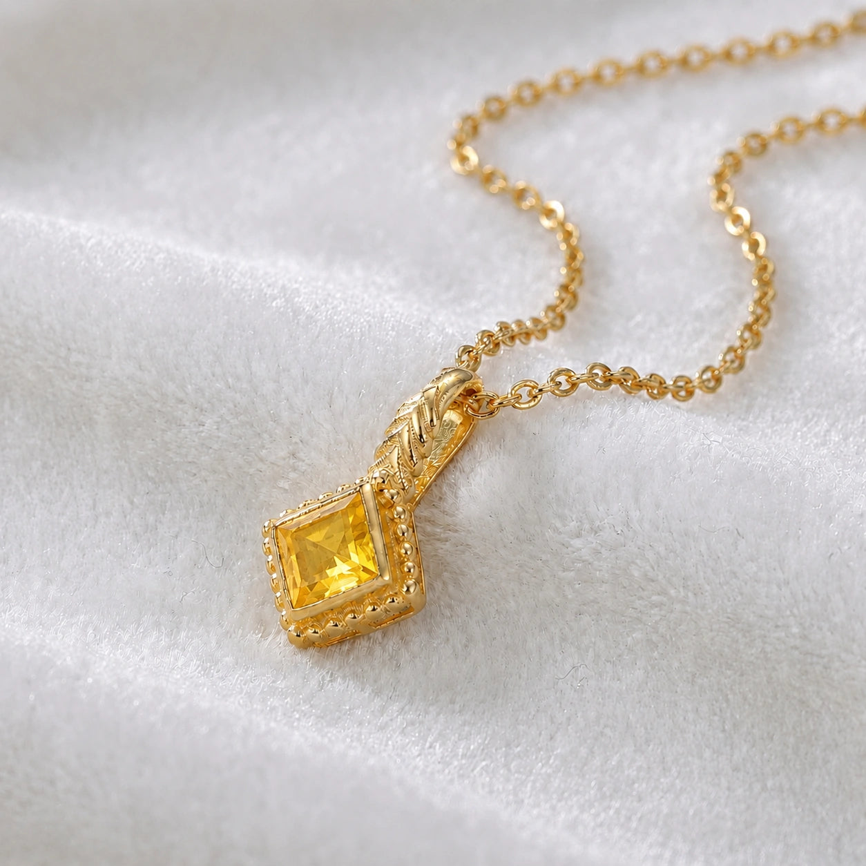 Birthstone_necklace_in_gold_plated_silver_with_square_cut_yellow_sapphire_pendant_in_slighlty_angled_view_on_soft_white_fabric_background