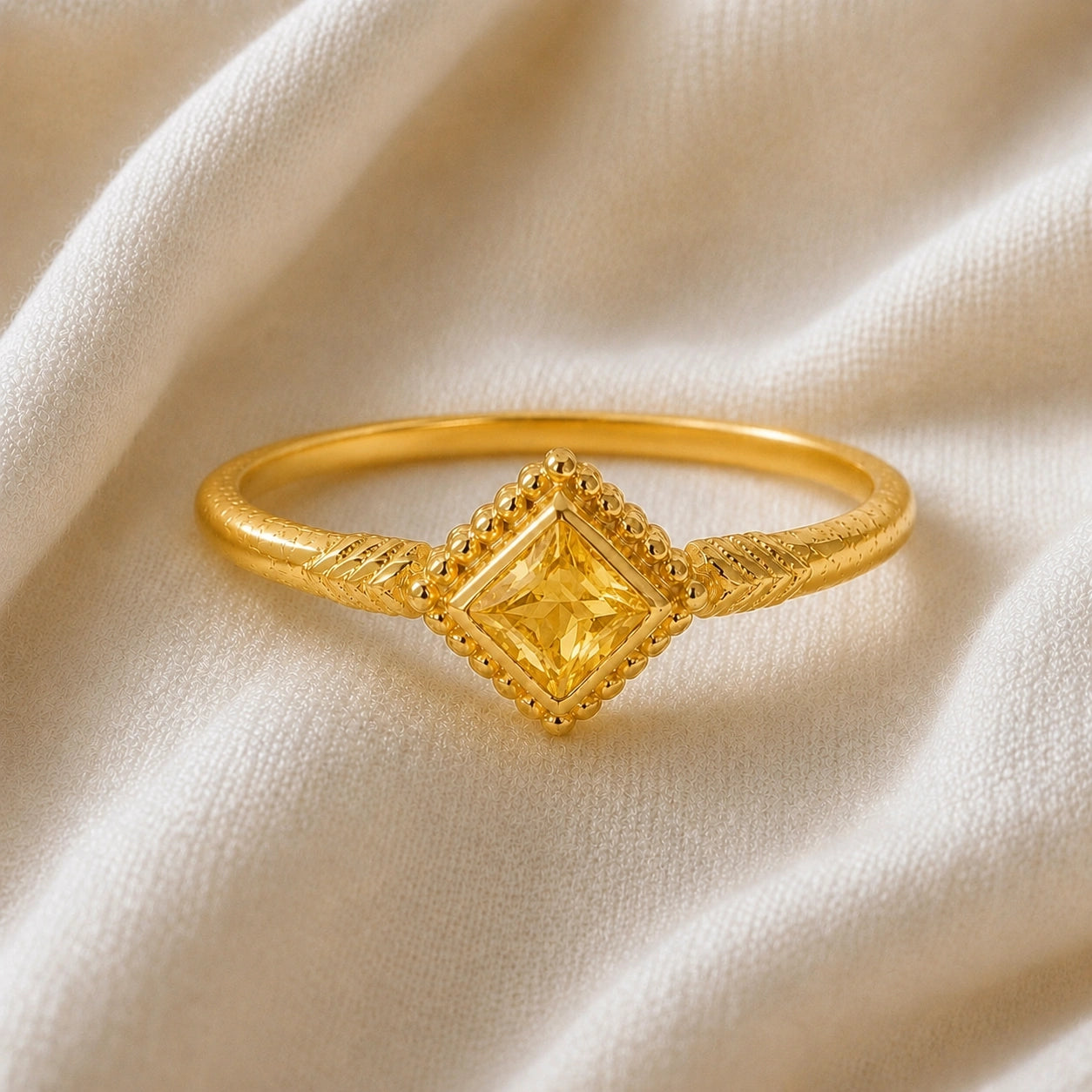Princess_cut_ring_gold_plated_silver_with_square_yellow_sapphire_and_detailed_band_front_angle_view_on_soft_fabric_background