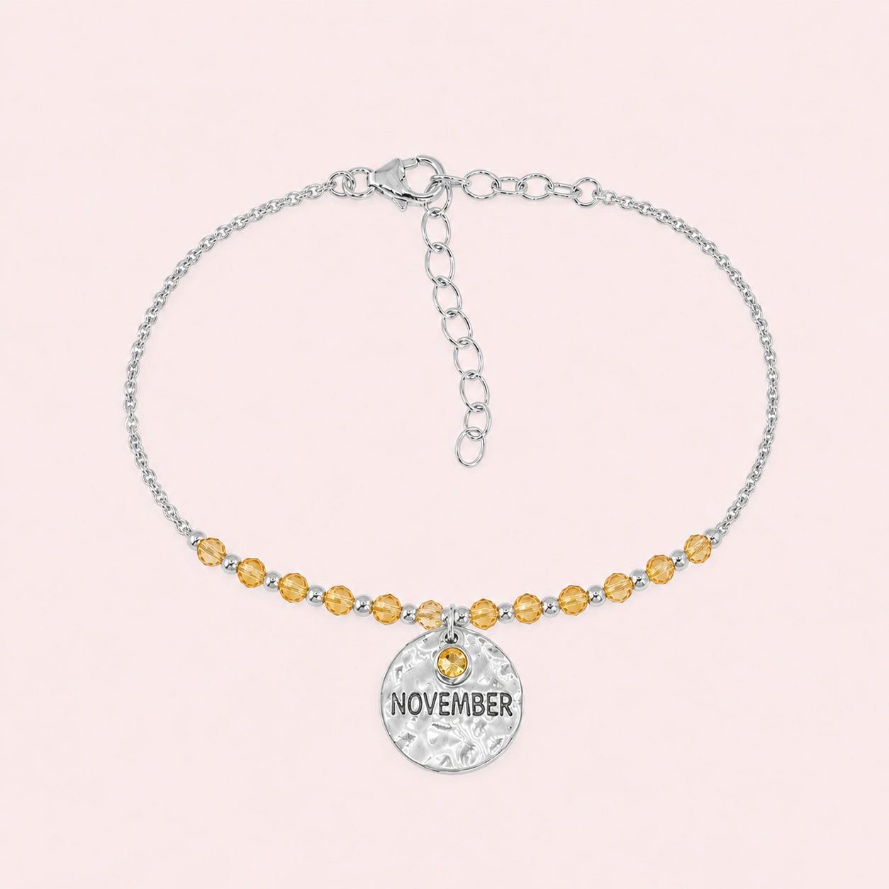 Birthstone_bracelet_in_sterling_silver_with_November_charm_and_yellow_topaz_beads_on_fine_chain_on_solid_pink_background