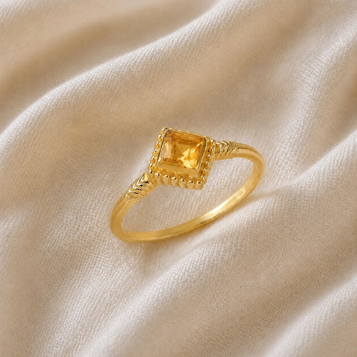 Princess_cut_ring_gold_plated_silver_with_square_citrine_and_detailed_band_slightly_tilted_view_on_soft_fabric_background