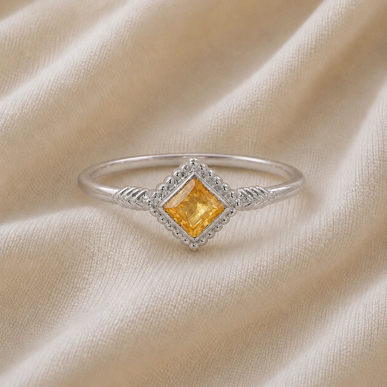 Princess_cut_ring_sterling_silver_with_square_citrine_and_detailed_band_front_angle_view_on_soft_fabric_background