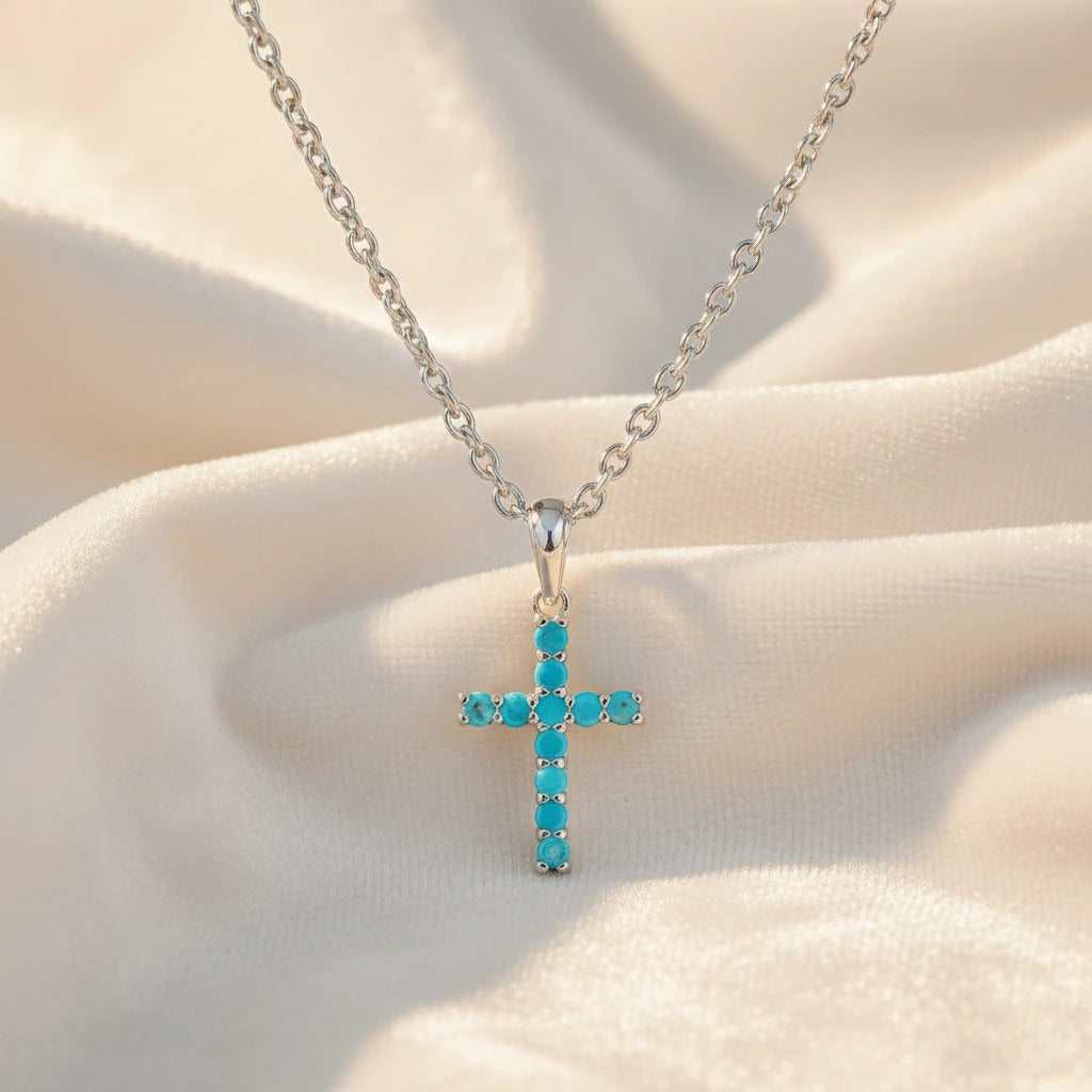 Front angle view of sterling silver cross pendant necklace and turquoise cross necklace on a white textured fabric background